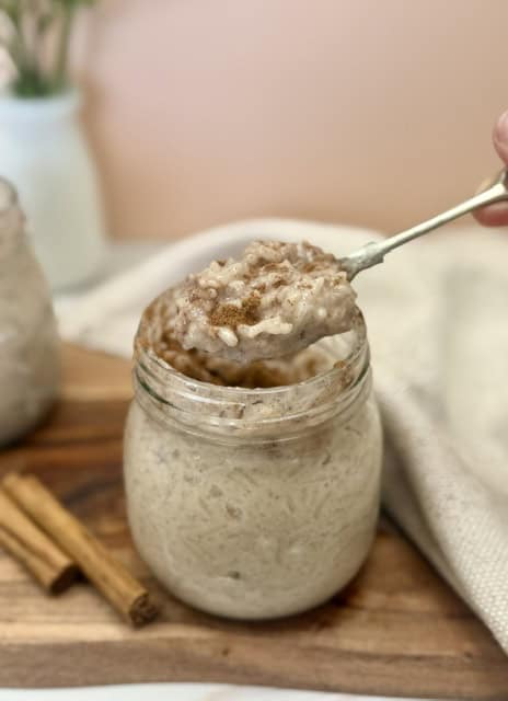 Creamy vegan rice pudding served in a glass jar with a spoon.