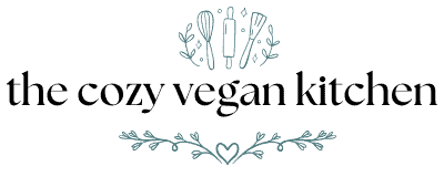 Logo for the cozy vegan kitchen with elegant black text, leafy decorations, a heart, and simple kitchen utensils like a whisk, spatula, and rolling pin illustrated above the text.