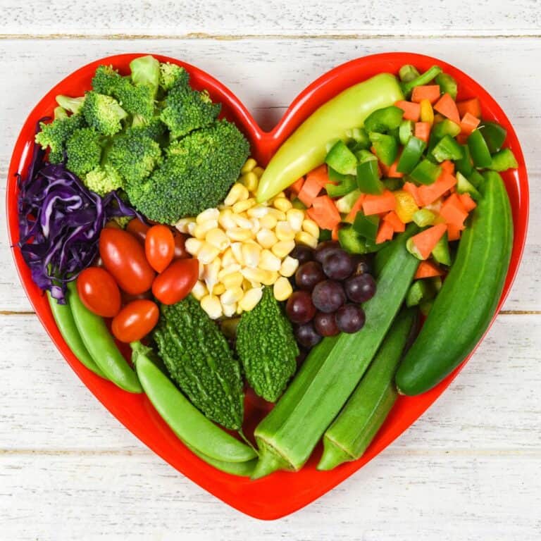 Colorful vegan vegetable platter in a heart shape for healthy eating.