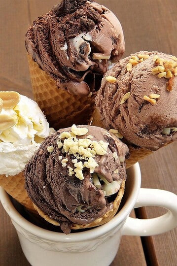 Assorted vegan ice cream cones with various flavors and toppings in a cup.