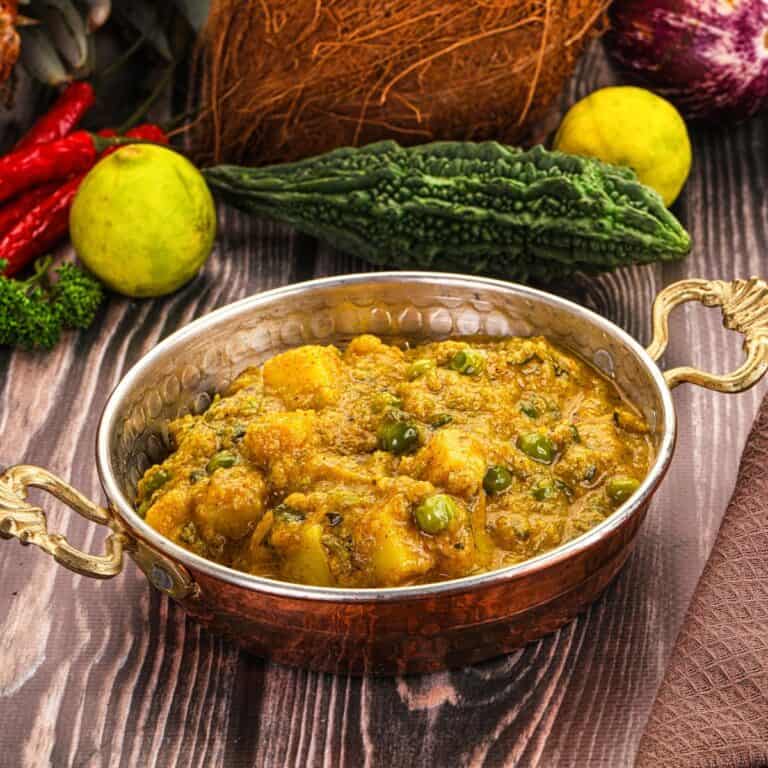 Vegan Indian potato curry with peas in a copper serving dish.