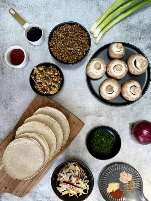 Vegan lentil tacos with mushrooms, onions, and fresh herbs on a rustic table.