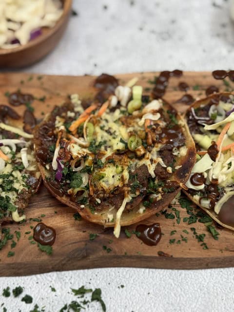 Vegan nachos topped with vegetables, vegan cheese, and drizzled with bbq sauce.